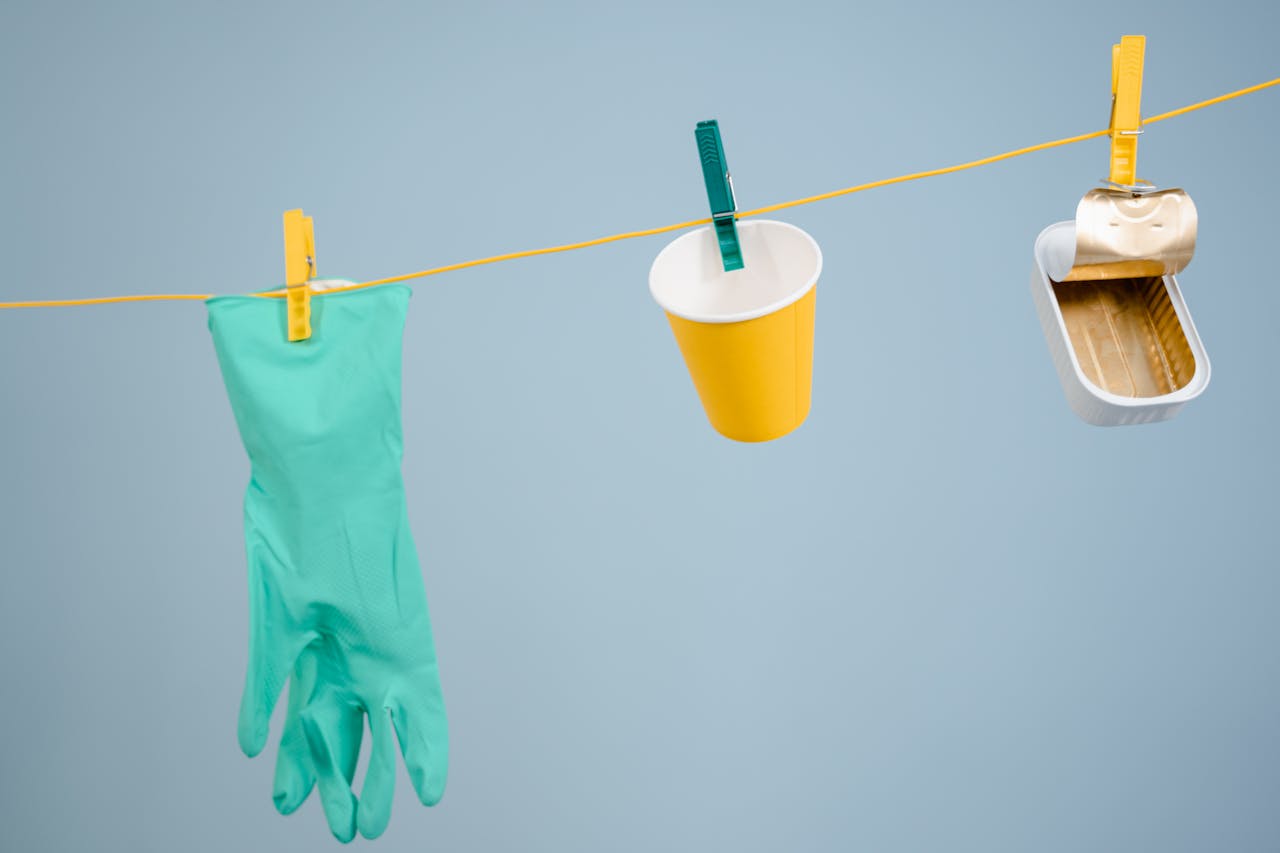 Innovative recycling concept with glove, cup, and tin can hanging on a line.