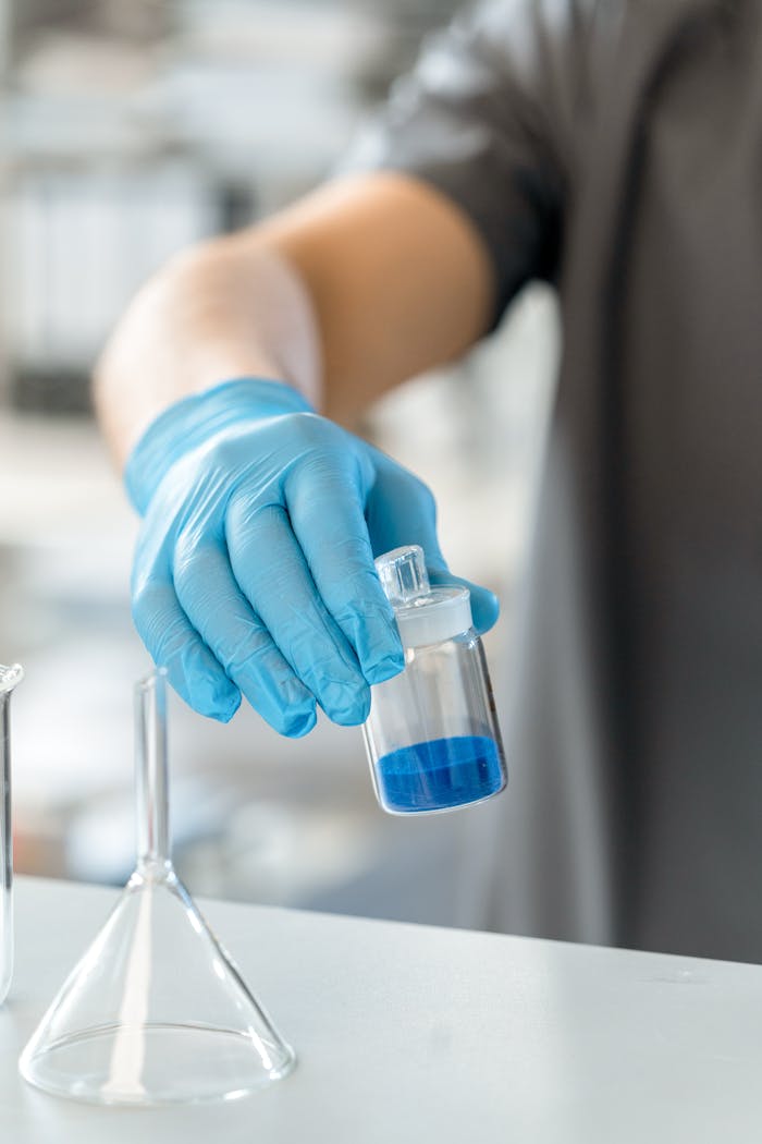 Close-up of a scientist using a lab apparatus to hold a blue solution in a research environment.